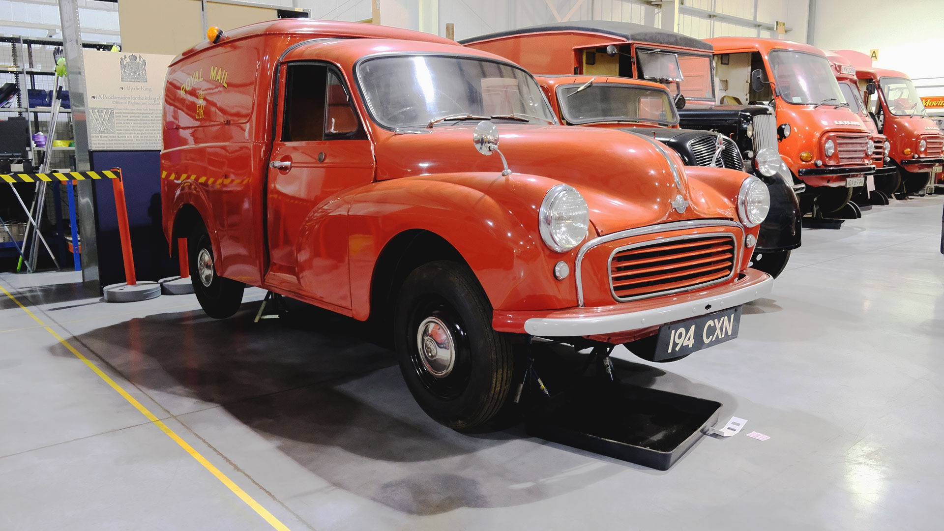 Post Office vehicles are lined up, with a red van at the front. This is part of the archive of exhibited vehicles at the Postal Museum Store in London.