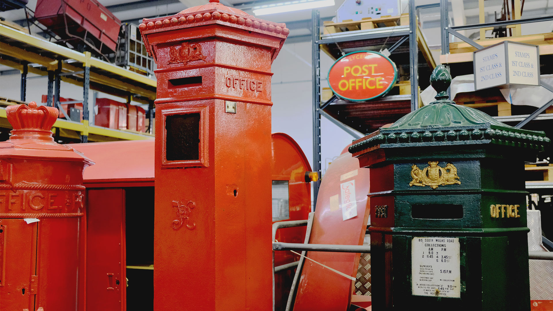 Red cast iron post boxes of different designs are lined up, including the Liverpool post box on the far left, which has a crown at its top.