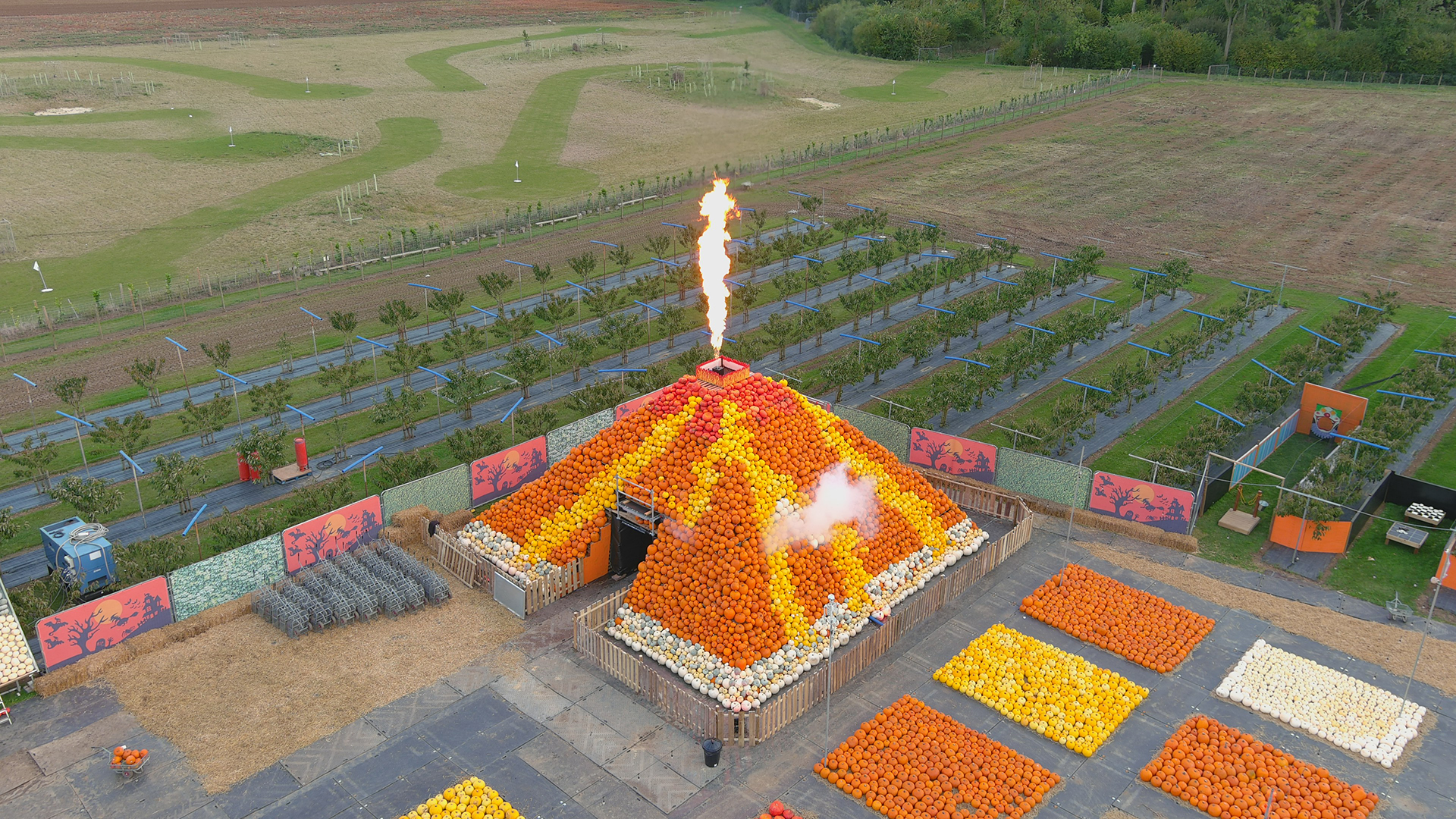 Fields with lots of different coloured pumpkins and a pumpkin volcano build of lots of pumpkins in yellow and orange spitting fire.