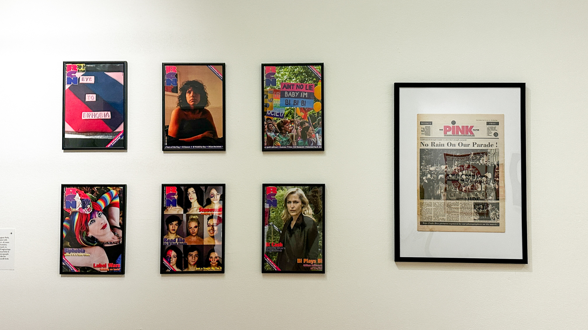 Covers and photography from The Pink Paper, one of Britain’s longest-running LGBTQ+ newspapers, highlighting queer media and representation. Image credit: Visit London/Kirstine Spicer Framed magazine covers and photographs displayed on a museum wall, alongside a framed issue of The Pink Paper newspaper.