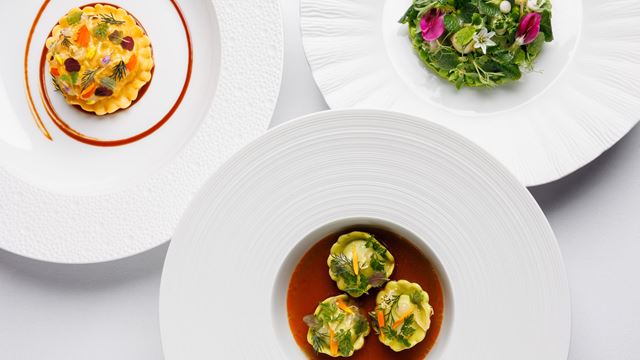 An overhead view of three of Restaurant Gordon Ramsay's dishes, on white plates.