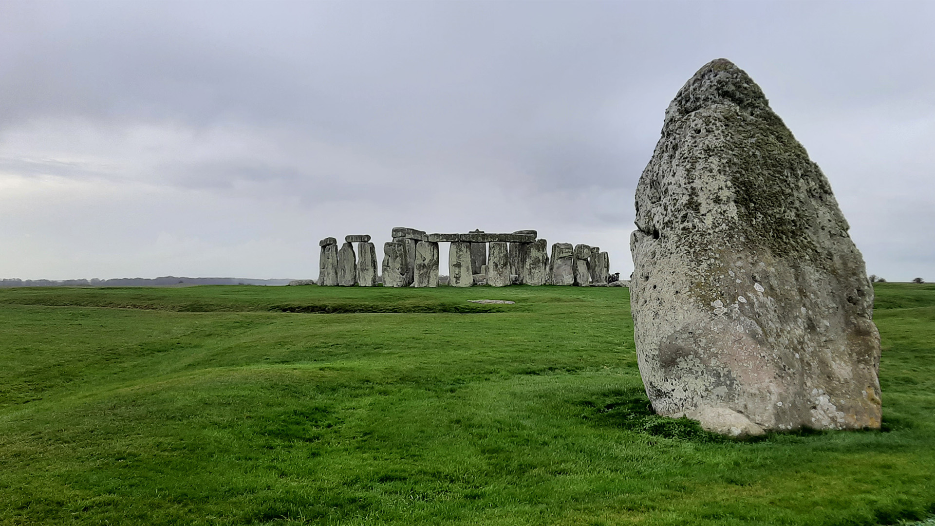 The stone circle at Stonehenge from further away with a free standing bolder in the forefront. 