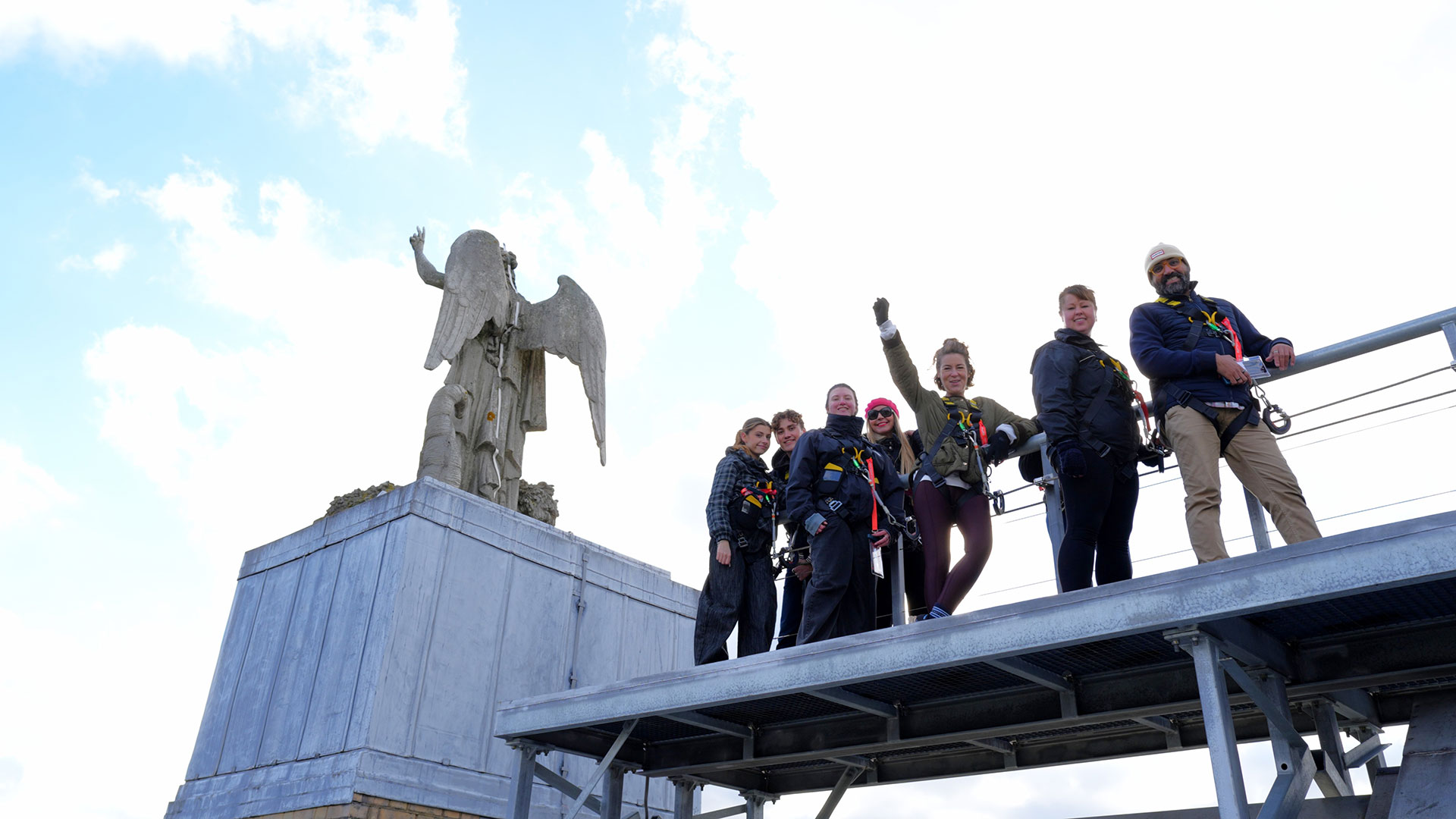 A group of people standing on a small viewing platform in from of the Angel of Plenty statue at Alexandra Palace.