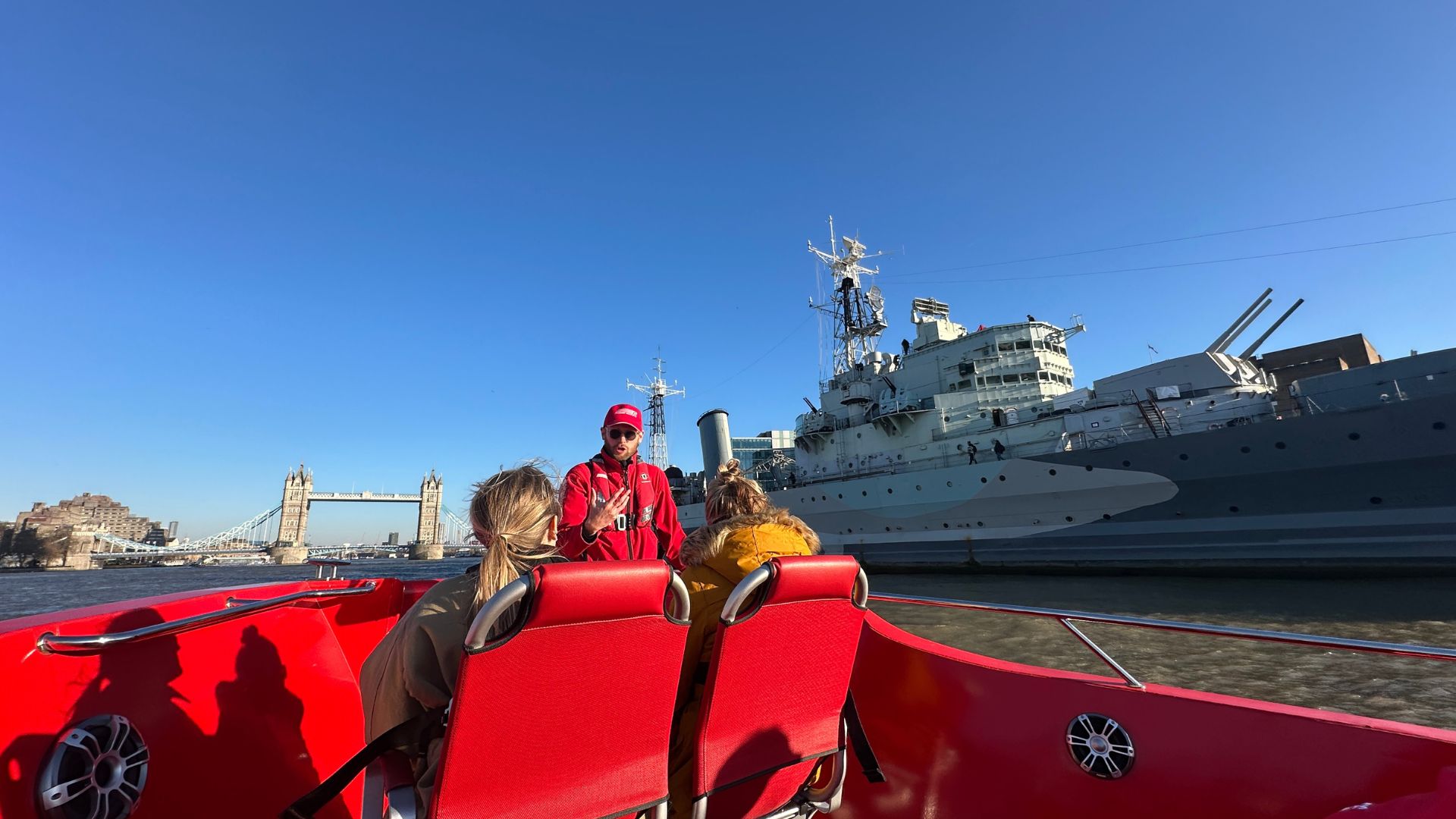 Passengers aboard the Rocket Rebel speedboat pass HMS Belfast on the River Thames.