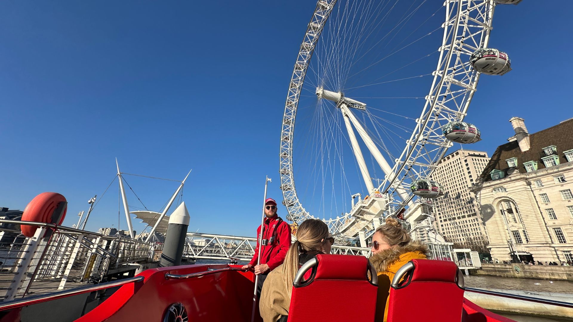 Passengers ride the Rocket Rebel speedboat along the Thames with London landmarks in view.