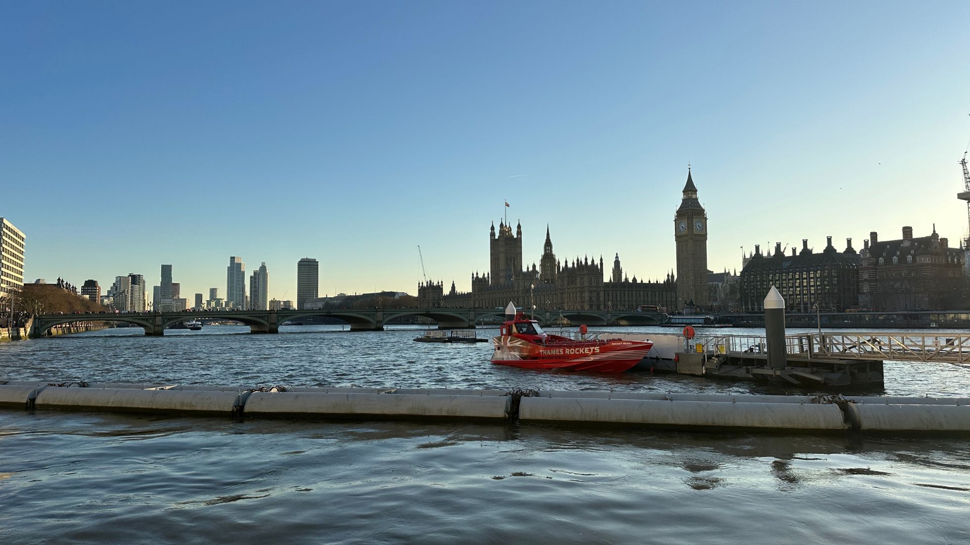 A Rocket Rebelsits on the River Thames with the Houses of Parliament and Big Ben in the background at sunset.