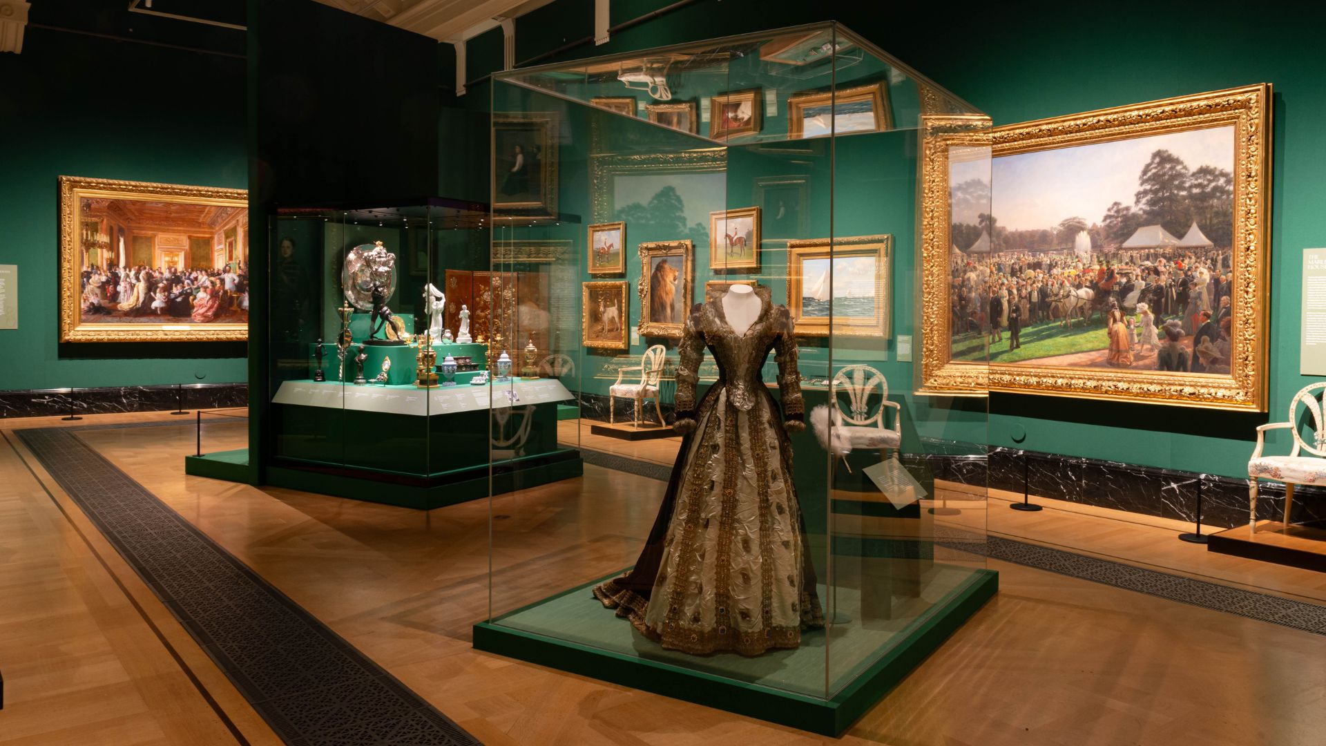 A dress and artwork reflecting the Edwardian royals in green gallery room.