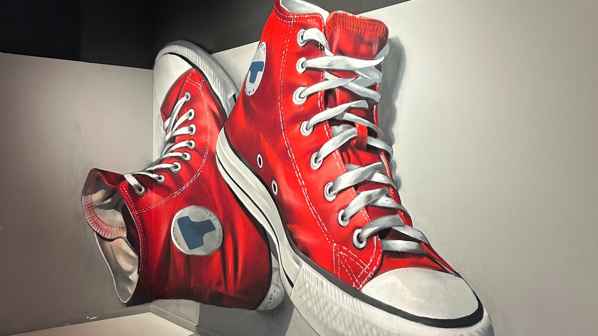 a large pair of red Converse trainers painted on to a white wall, giving the illusion that they are floating in the air