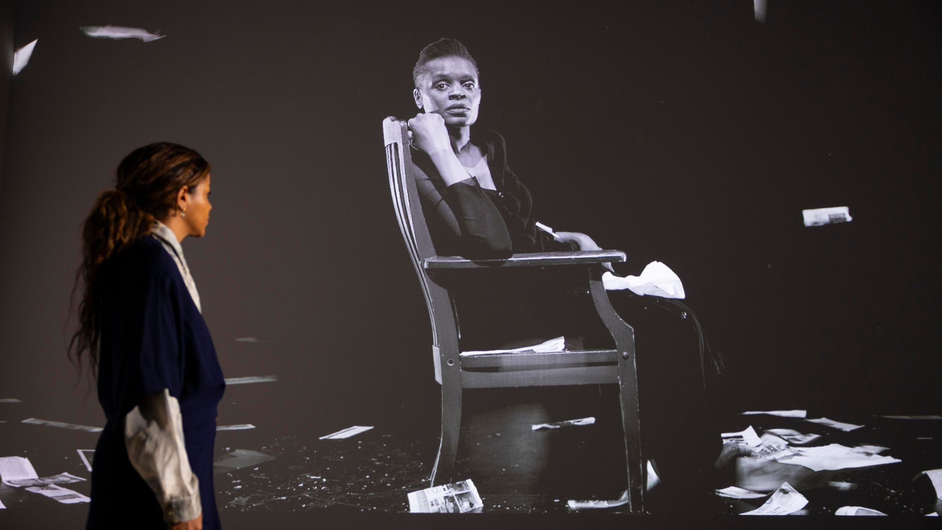 Carrie Mae Weems's film The Long Goodbye in the background with person looking back at it.