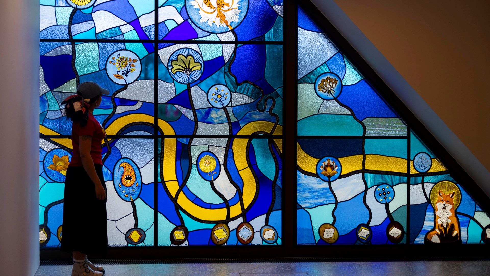 Blue patterned stain glass window with person looking out to it.