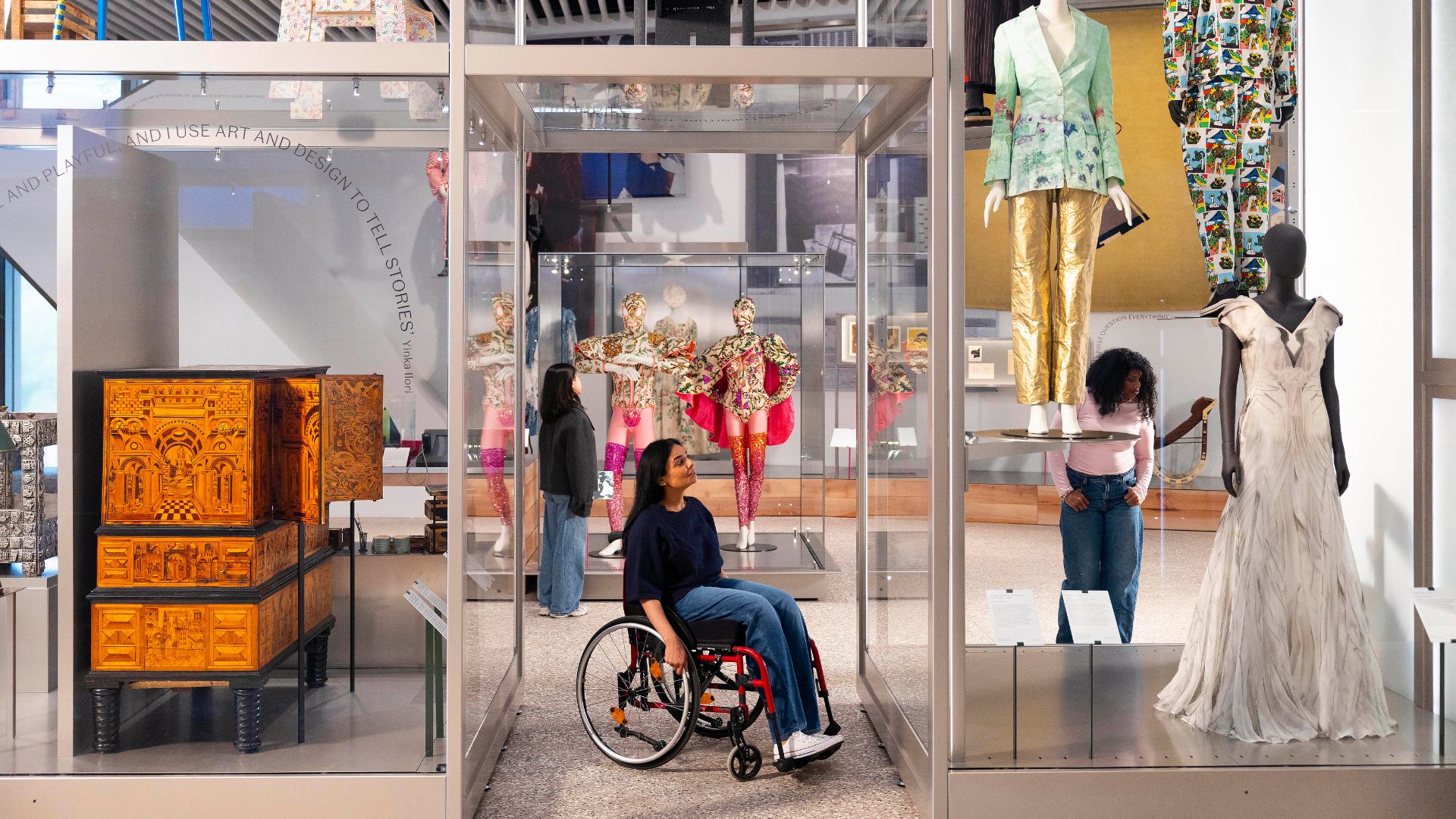 Museum exhibits arranges in a shop front formation with costumes in glass case.