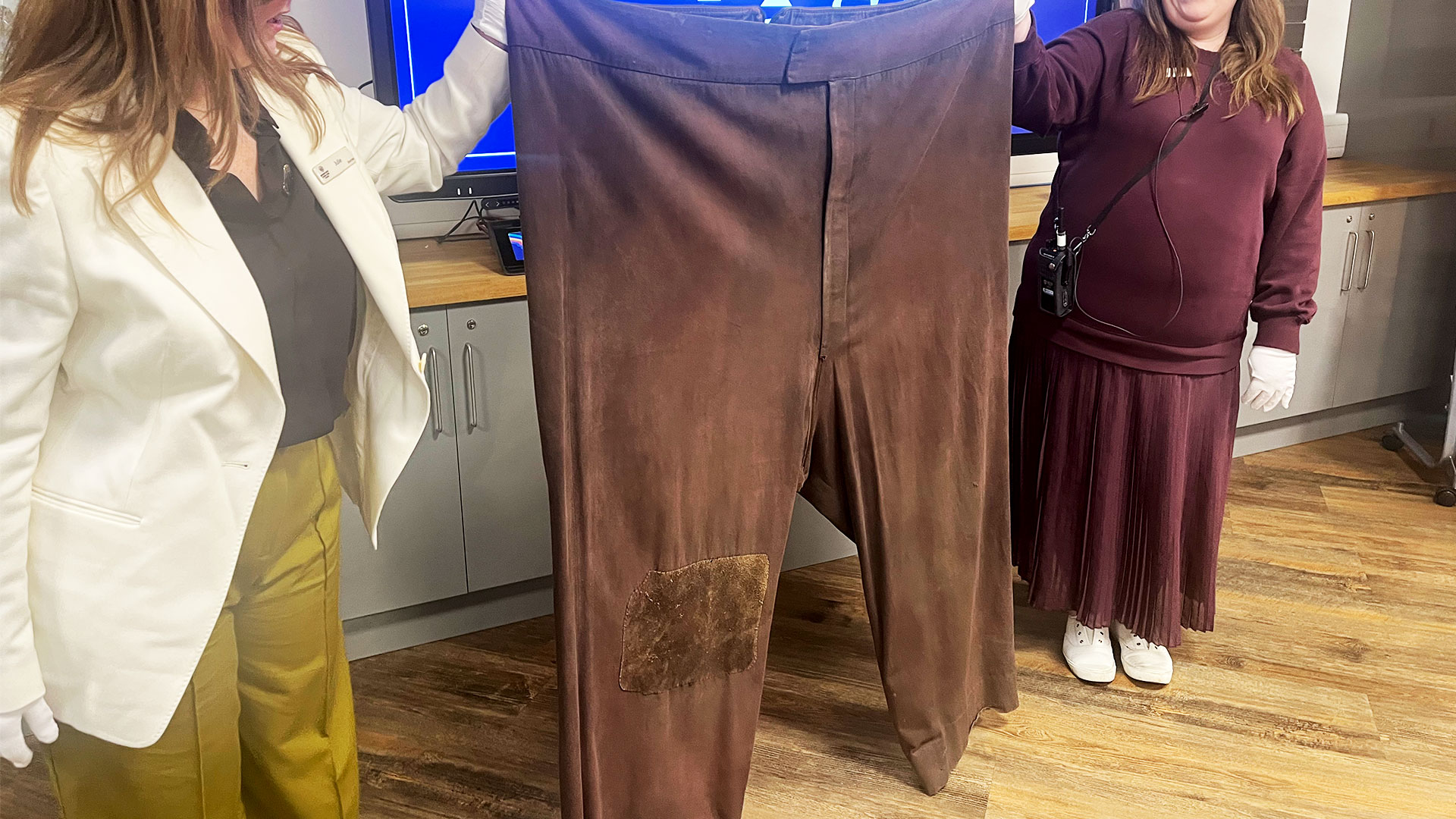 At the costume workshop held at the Warner Bros. Studio Tour, two women are holding up the enormous brown trousers of half-giant Rubeus Hagrid.