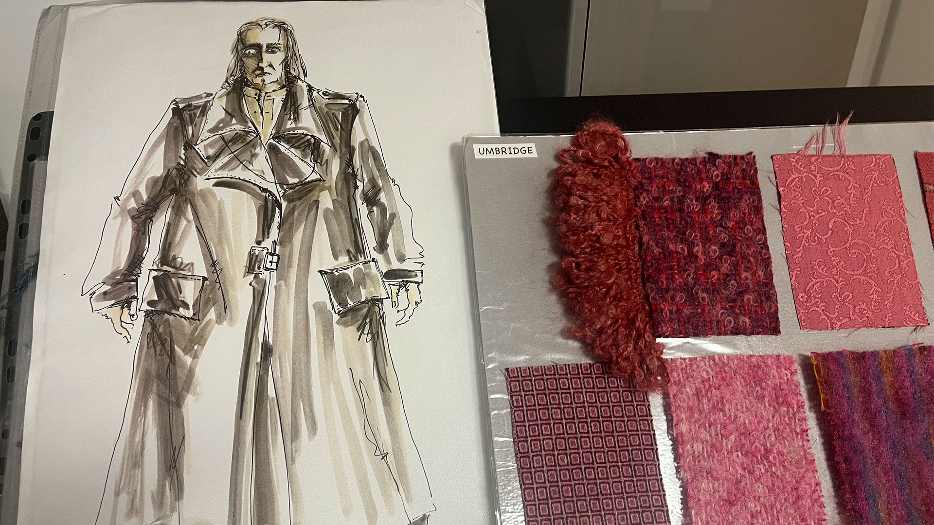 A watercolour sketch of the Maugrey Mad-Eye costume, placed next to a selection of pink fabrics to be used for Umbridge's costumes.
