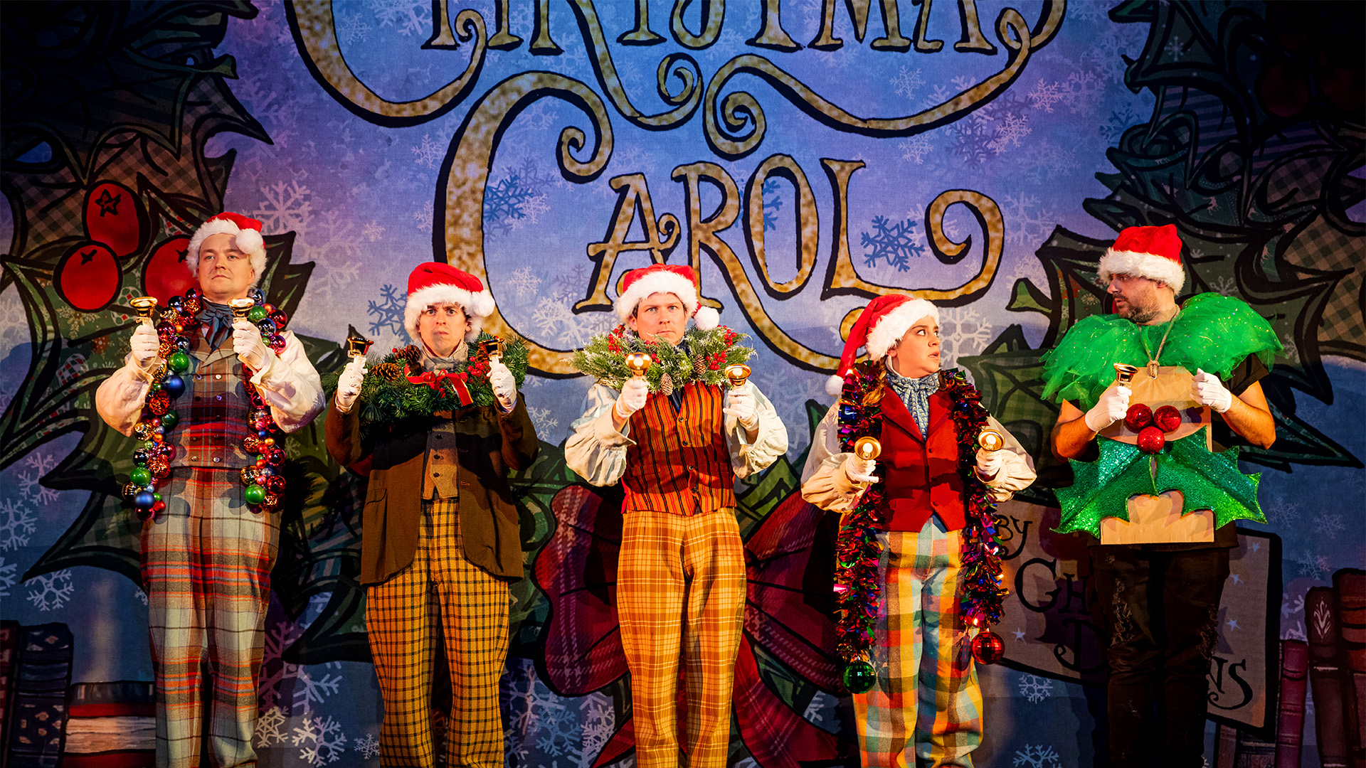 Four cast members dressed in Santa hats in Christmas Carol Goes Wrong