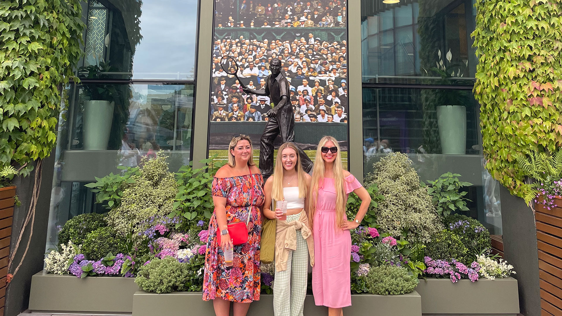 Soak up the atmosphere as you wander the grounds outside the iconic Centre Court at Wimbledon. Image courtesy of Chantal Welch. Three girls standing in front of the Fred Perry statue at Wimbledon