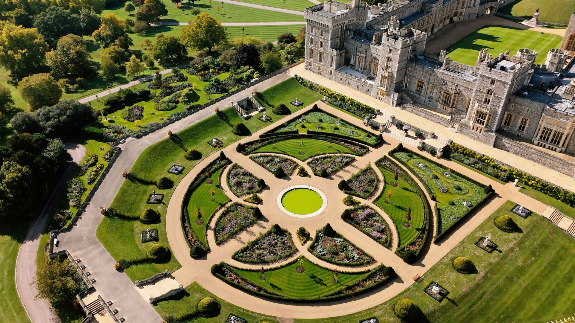 Aerial view of the Venus Garden at Windsor Castle showing circular flower beds, curved pathways and a central fountain beside the castle’s east façade.