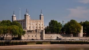 Der Tower of London vom Fluss aus gesehen, an einem sonnigen Tag mit klarem Himmel im Hintergrund.