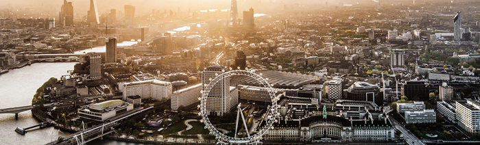 London skyline at dusk, featuring the London Eye, the river Thames and other iconic London buildings.