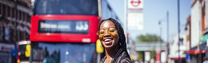 Une femme se tient dans les rues de la capitale anglaise al:lors qu'un bus rouge approche.