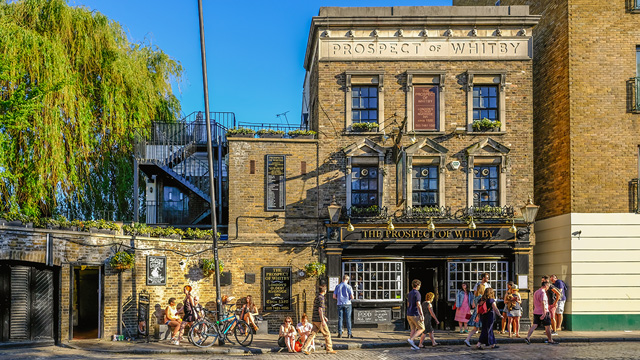 People enjoy drinks in the sunshine outside the Prospect of Whitby pub