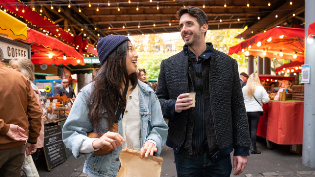 Smiling young couple enjoying a drink and a chat in a London street food market.