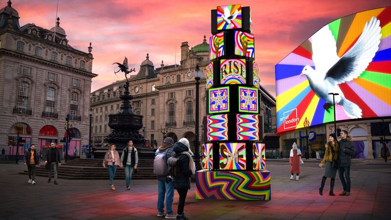 A couple stand in front of a large art installation in piccadilly circus, London.