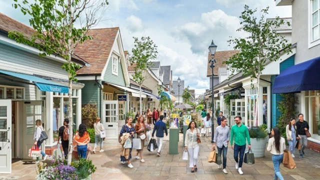 Des personnes marchent au coeur de la destination shopping Bicester Village, connue pour ses magasins de grand nom.
