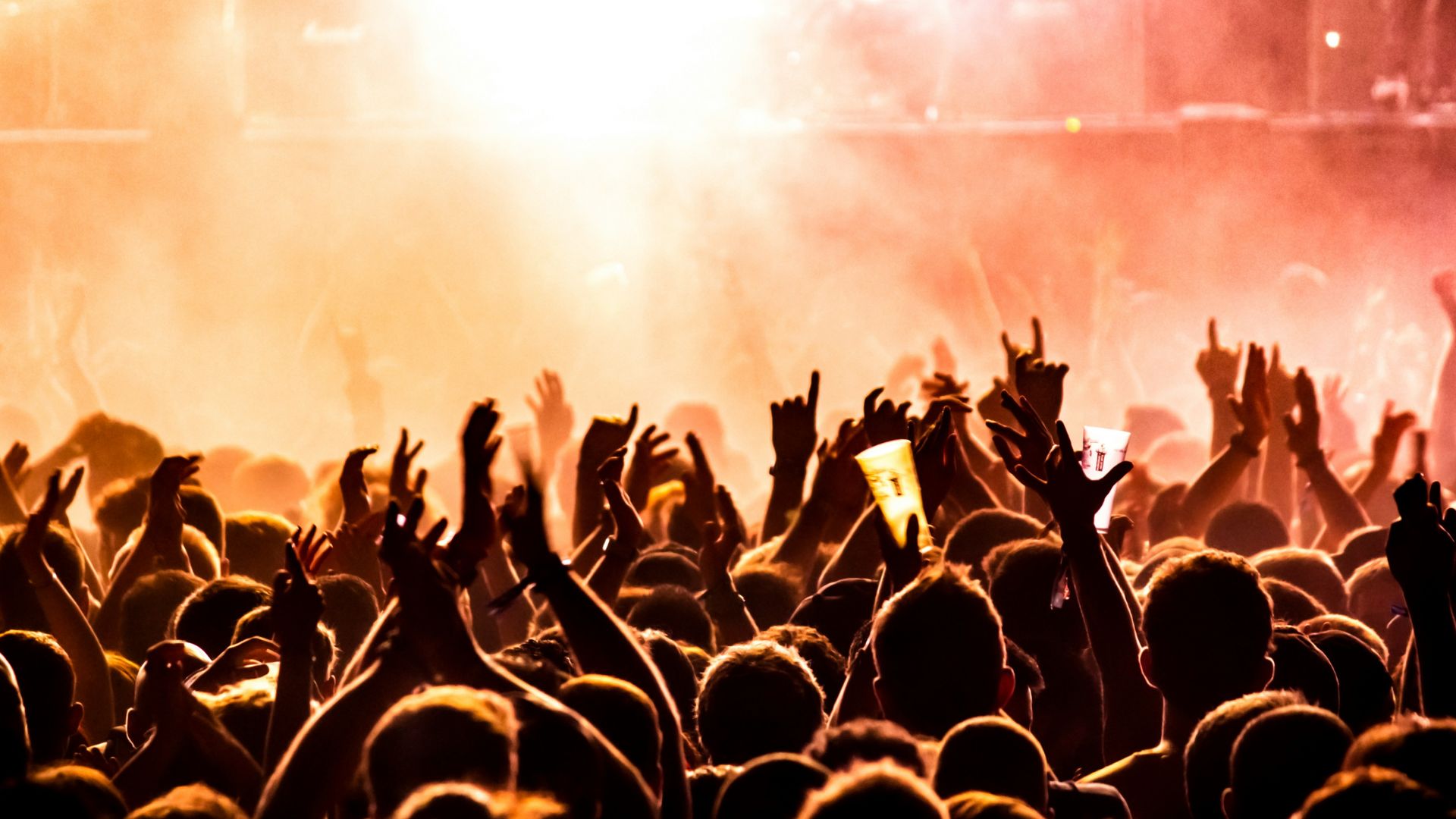 Crowd dancing to live music with red and yellow lighting.