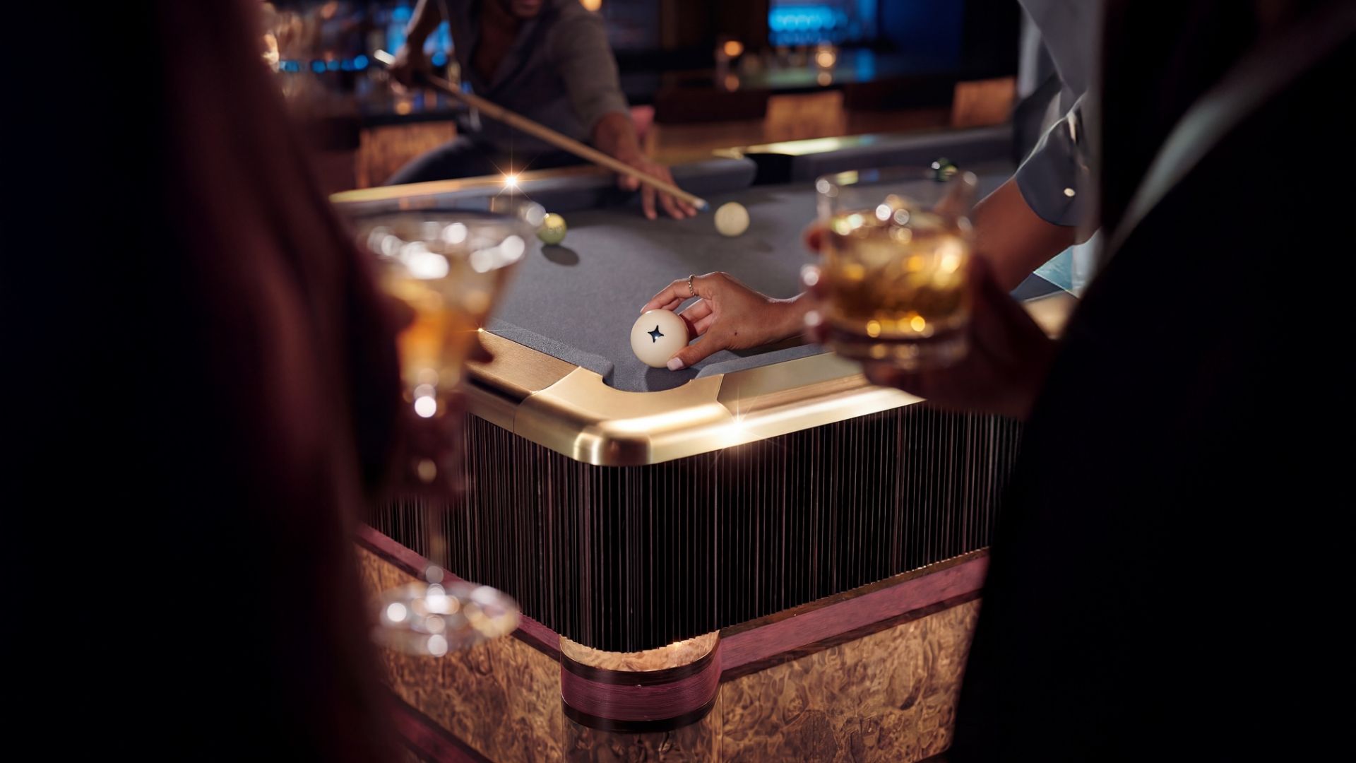 Guests playing pool at Poolhouse in London, with drinks in hand around a technology-enhanced pool table in a stylish, atmospheric venue.