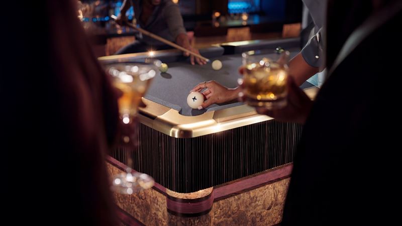 Guests playing pool at Poolhouse in London, with drinks in hand around a technology-enhanced pool table in a stylish, atmospheric venue.