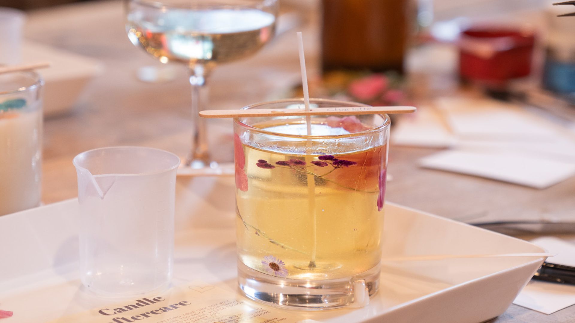 Get creative at a candle-making class with ArtPlay, where you can make your own personalised scented candle. Image courtesy of ArtPlay. A handmade candle in a glass tumbler decorated with dried flowers, sitting on a tray during an ArtPlay candle-making class in London.