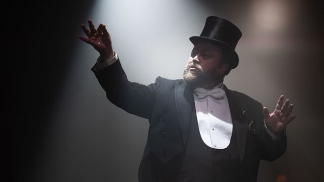 Dressed in a top hat and tuxedo, Neil Kelso portrays a magician and illusionist at CHAT NOIR!