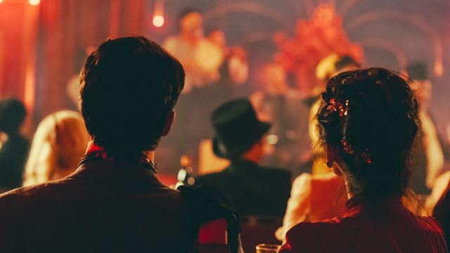 Guests seated in a dimly lit cabaret-style venue watching a live performance on stage at CHAT NOIR