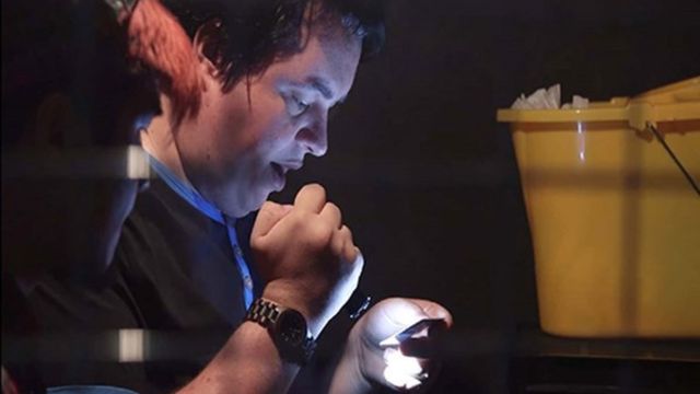 A man uses a torch to look at an escape room puzzle.