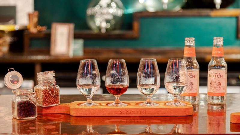 Sample a selection of Sipsmith spirits and mixers while exploring the botanicals that shape each flavour. Image courtesy of Golden Tours. A tasting flight of Sipsmith spirits served in four glasses with botanicals and tonic water on a wooden tasting board.