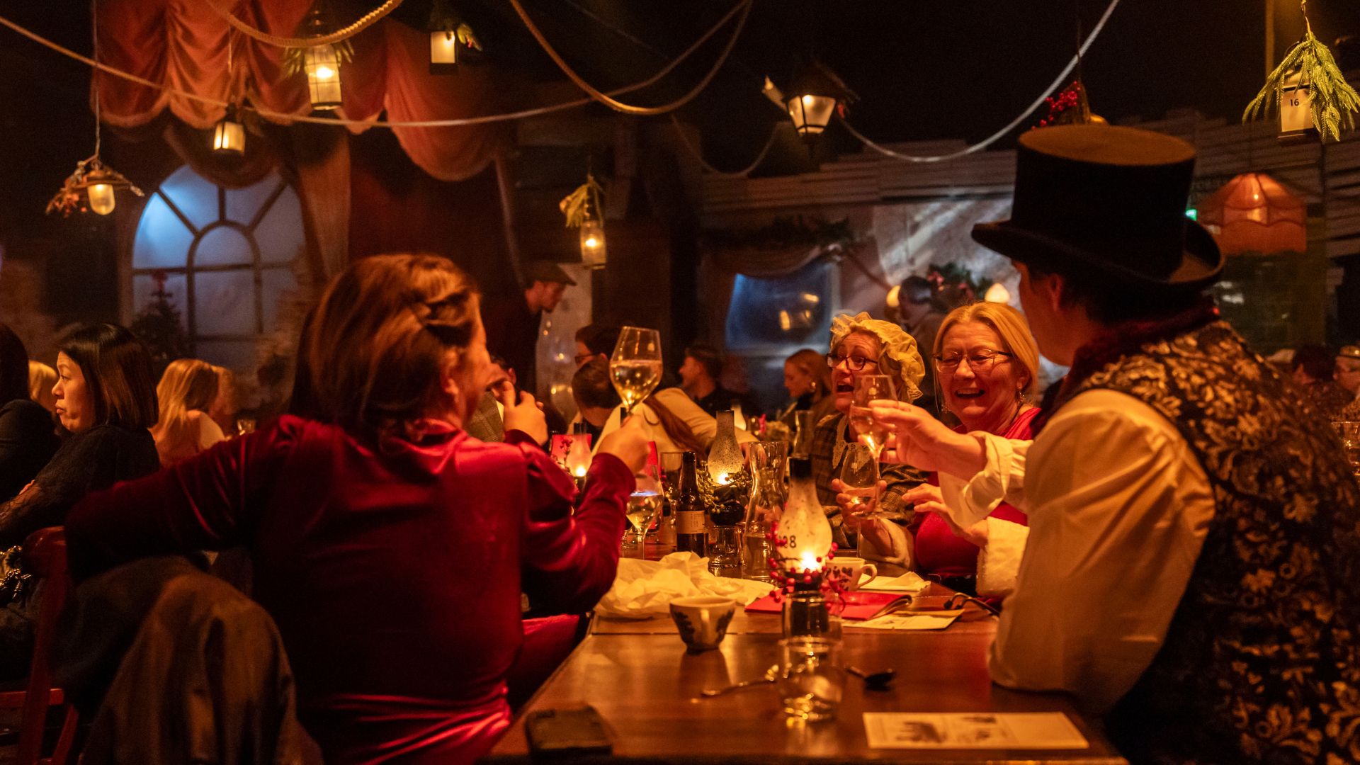 Be immersed in the festive cheer at The Great Christmas Feast. Image courtesy of The Lost Estate. A table of people in a room with christmas decorations enjoying a christmas feast.