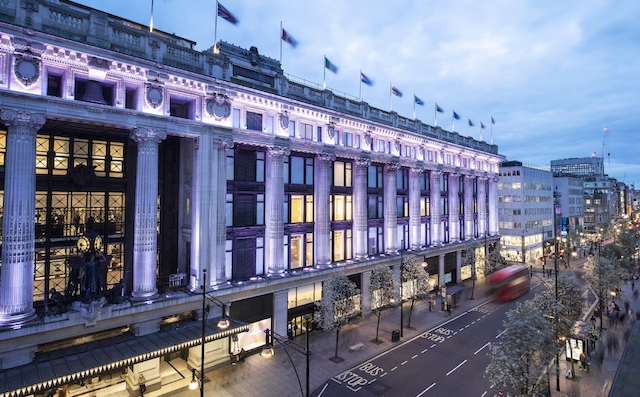 Oxford Street has many famous shops, including Selfridges. ©Andrew Meredith/Selfridges. Illuminated exterior of Selfridges department store on Oxford Street in London at dusk.