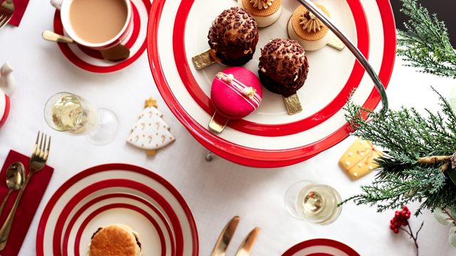 Ein festlich gedeckter Tisch mit bunten Tellern mit weihnachtlichen Leckereien beim Biscuiteers Weihnachts-Nachmittagstee in London.