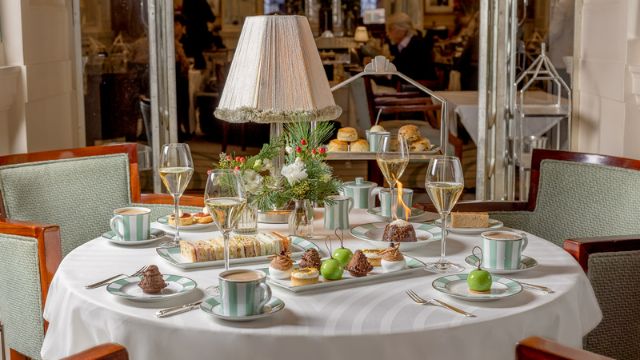 Ein herrlich gedeckter Tisch mit Champagner und süßen und herzhaften Leckereien für den weihnachtlichen Nachmittagstee im Claridge's in London.