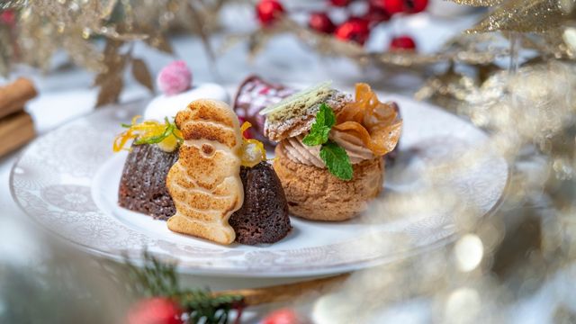 Ein weißer, weihnachtlich geschmückter Teller mit Weihnachtsgebäck und einem Holzscheit aus Schokolade beim Nachmittagstee im Conrad London Hilton.