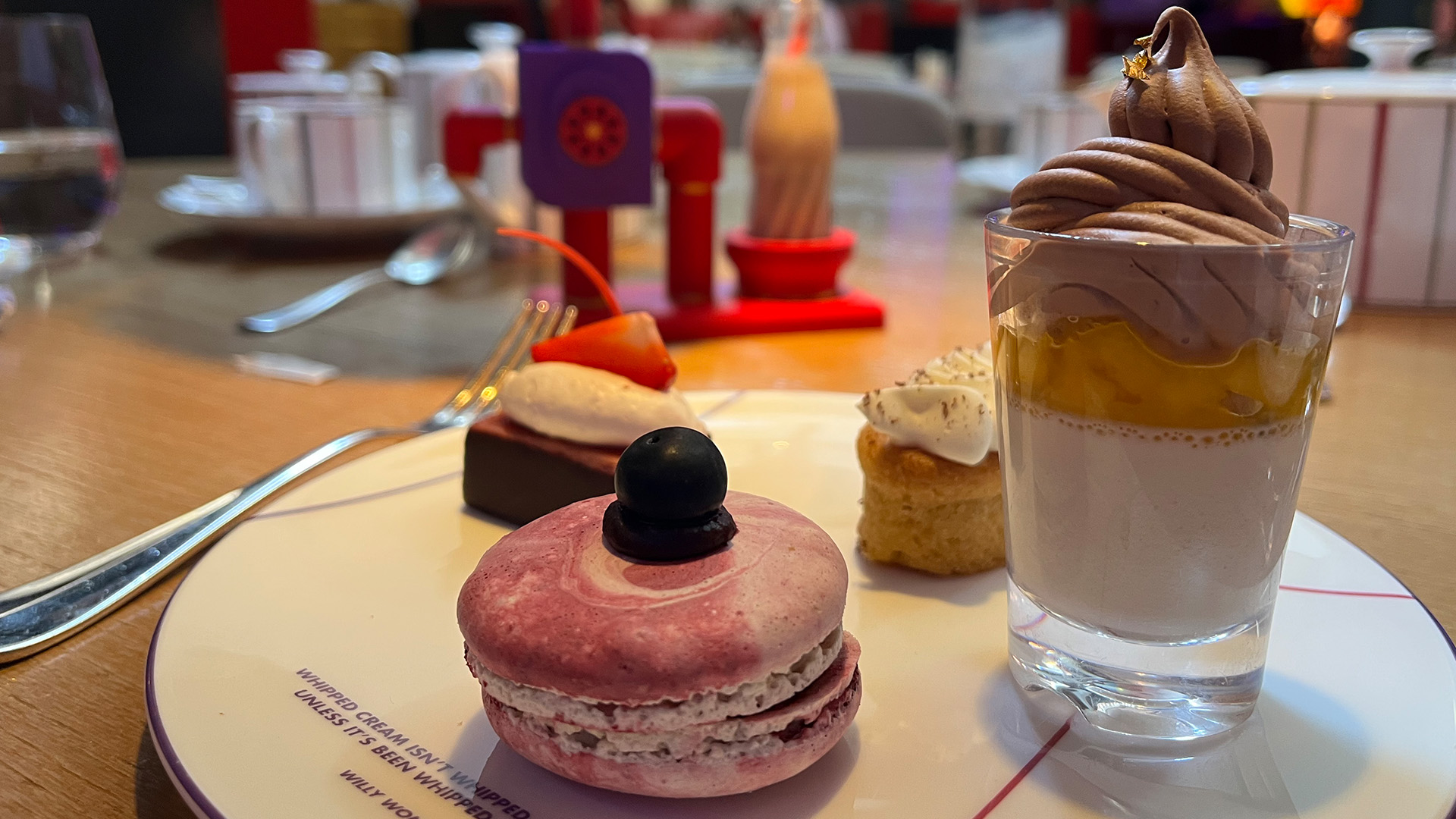Enjoy a vegan afternoon tea at One Aldwych. Image courtesy of Visit London/Carole Rocton. A plate with 4 sweet desserts, one glass with a white and chocolate mousse, a macaroon, and two small cake bites.