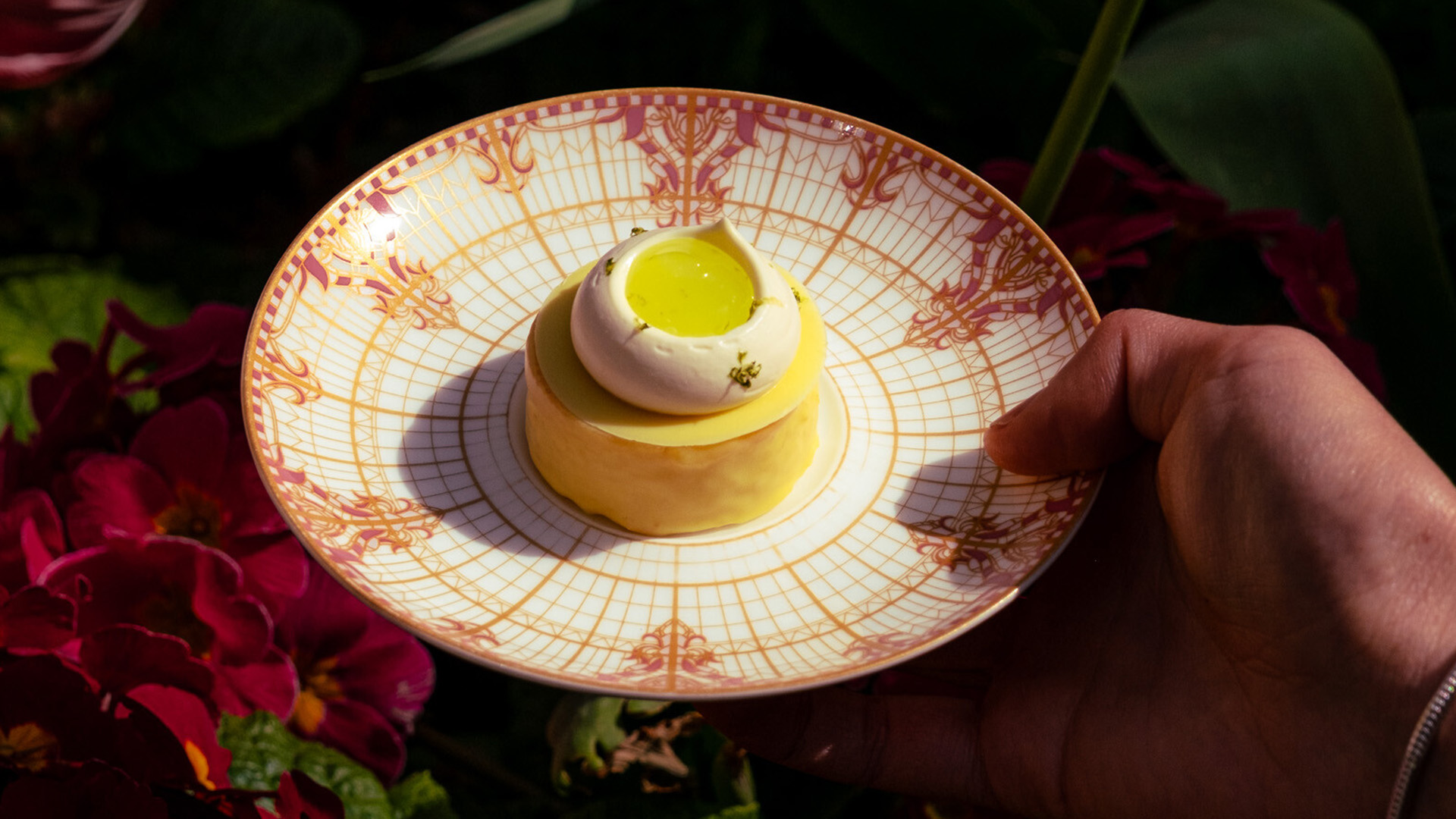 Image of a plate with a type of round yellow mini cake, with a white cream on top and some yellow cream inside that cream.