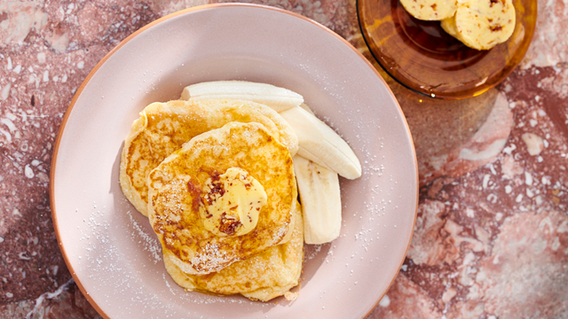A plate of ricotta hotcakes with fresh banana and honeycomb butter