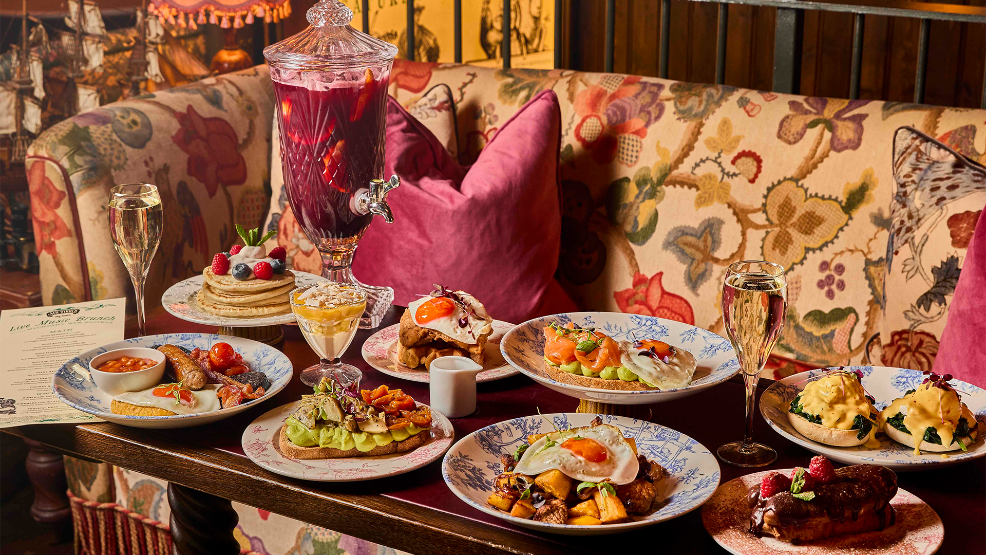 A spread of brunch dishes including eggs benedict, full english, pancakes, eggs royale, chicken and waffles, punch and prosecco