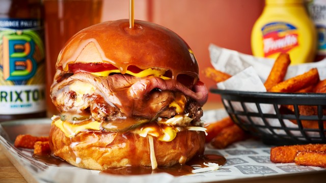 Close-up of a gravy beef burger with sweet potato fries and a Brixton beer in the background.