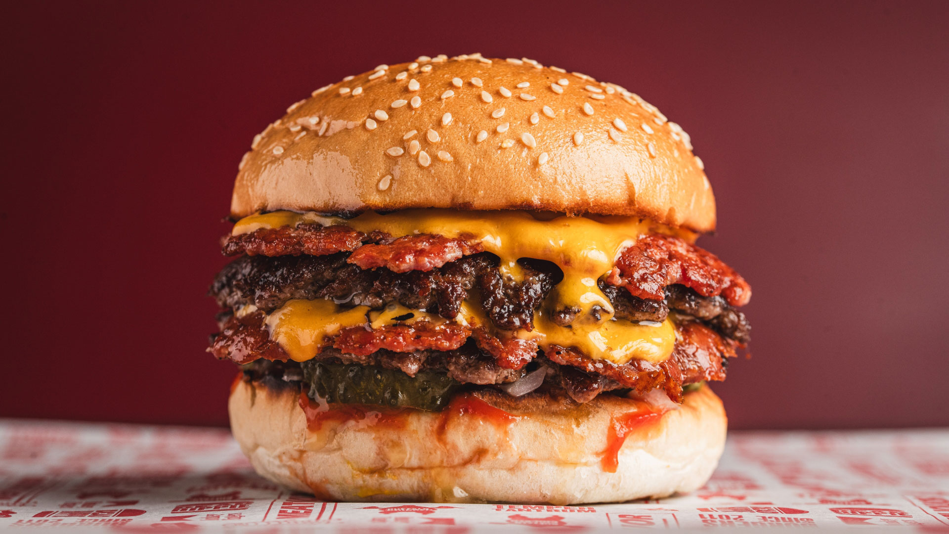 A photo of a burger at MEATliquor from the side with two beef patties, bacon and American cheese on a sesame bun