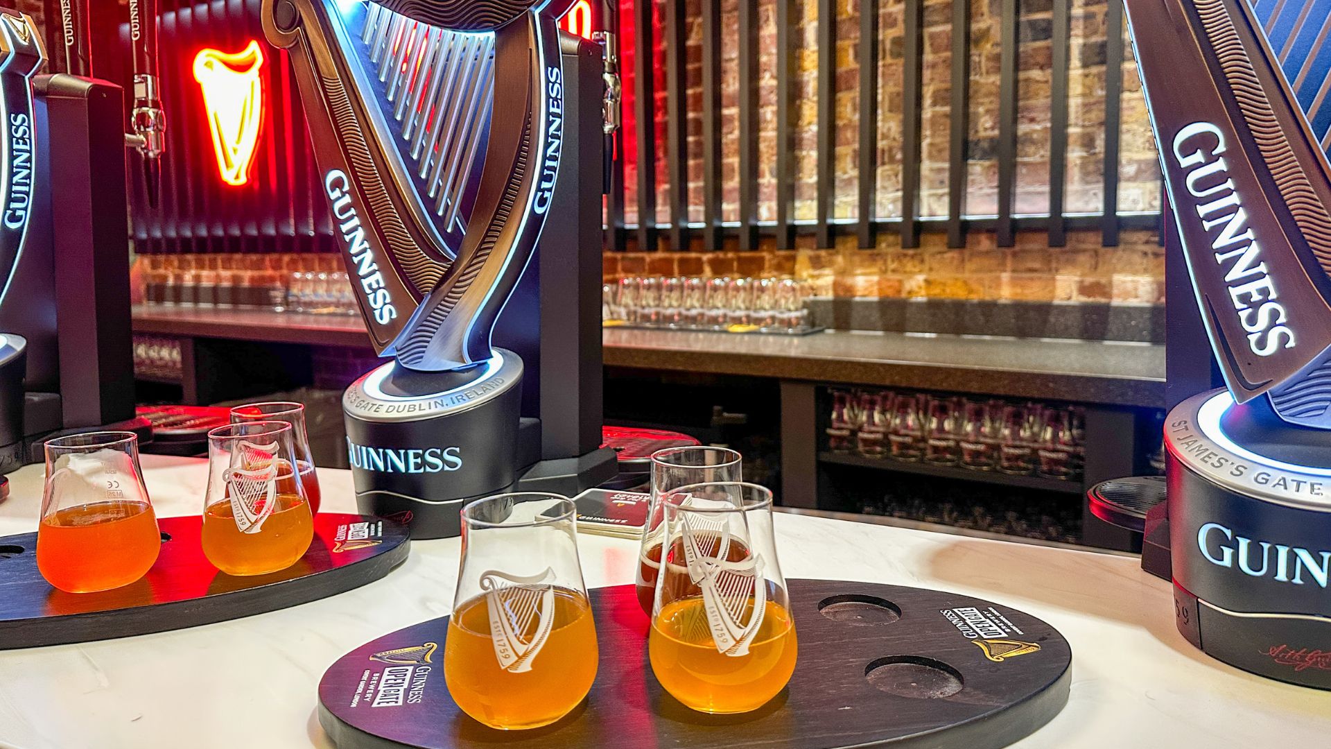 Playful Guinness design details can be spotted throughout the brewery, blending heritage with modern touches. Image courtesy of Kirstine Spicer. A Guinness beer tasting flight featuring small glasses of experimental beers on wooden paddles at the Guinness Open Gate Brewery London.