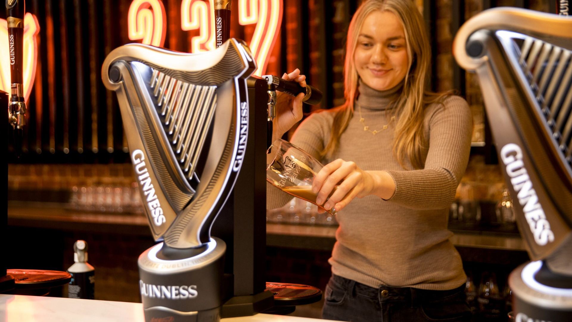 Woman pouring her own pint of Guinness inside Bar 232 at the Guinness Open Gate Brewery London.