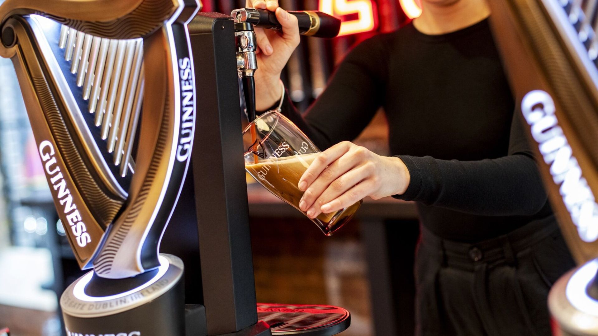 Person pouring a Guinness from a branded tap during the Guinness brewery tour in London.
