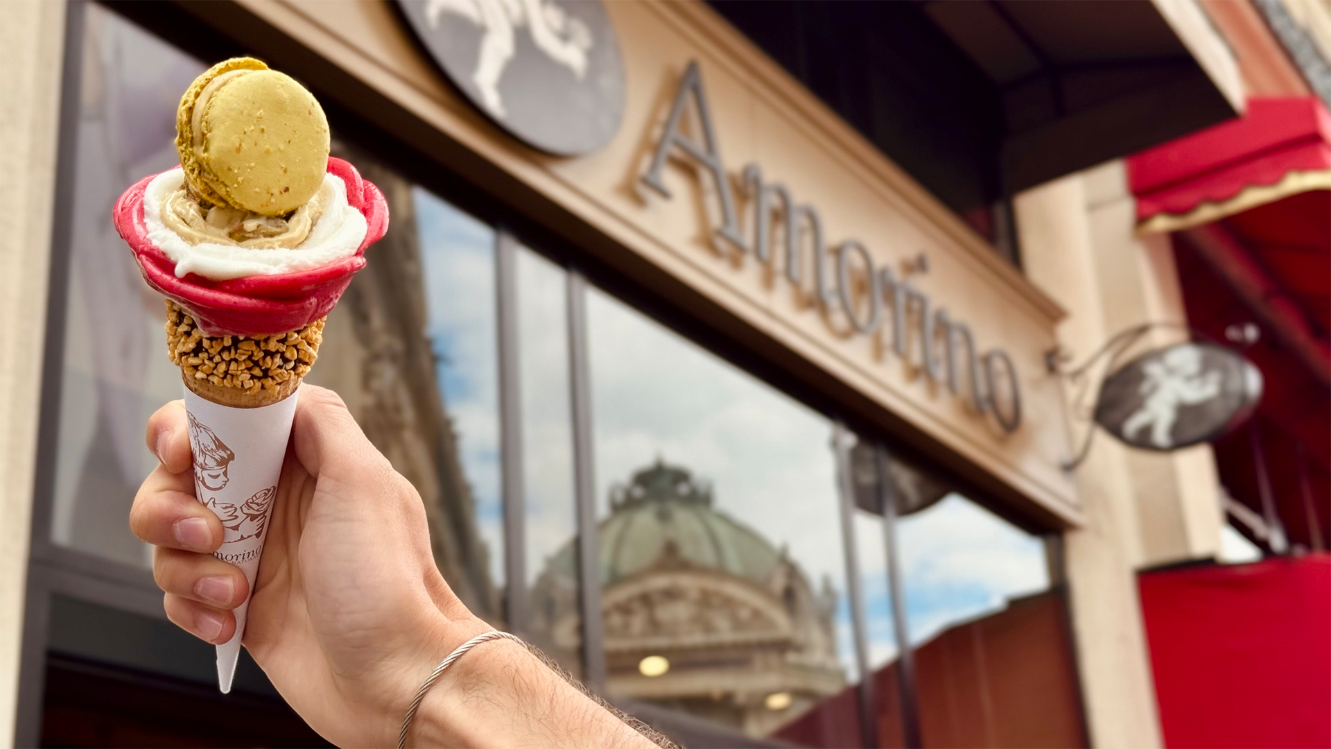 A person holding a rose-shaped ice cream against the Amorino shop front